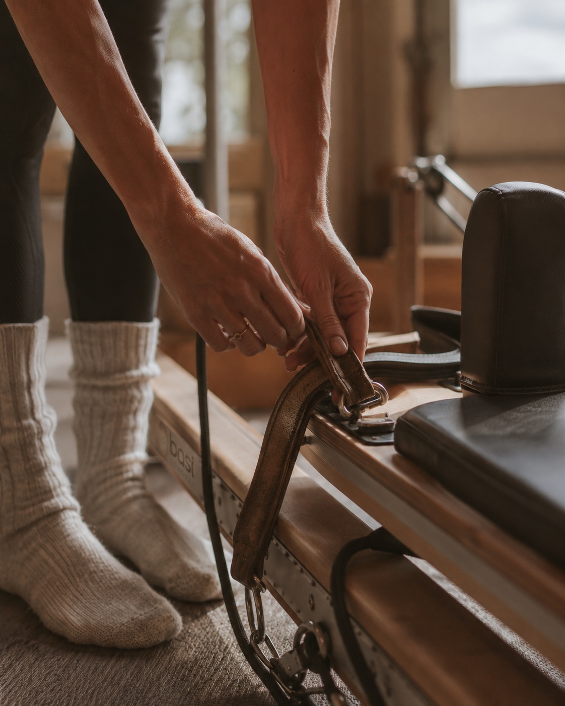Close-up of hands adjusting a reformer strap